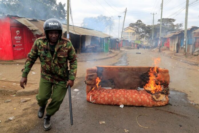 A riot police officer runs near a burning sofa, as supporters of Kenya's opposition leader Raila Odinga take part in an anti-government protest against tax hikes in Nairobi, Kenya on July 19, 2023 [Thomas Mukoya/Reuters]