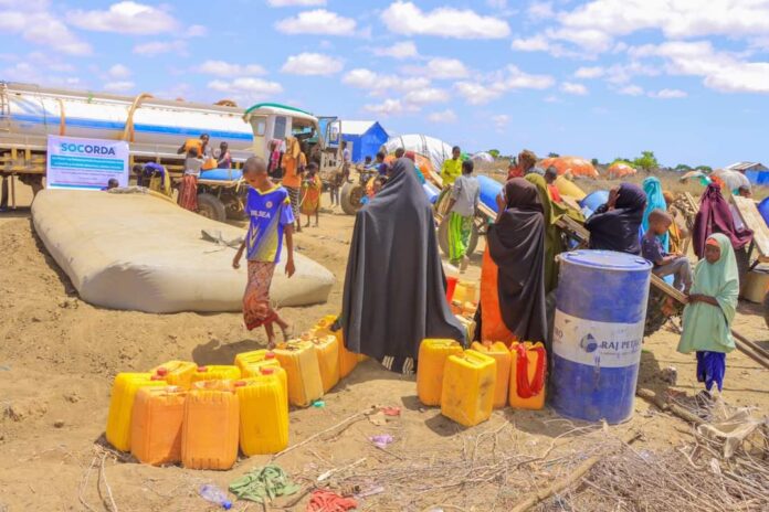 People gather to receive water brought by a local NGO at Galool Yaryar village, west of Kismayo, Somalia. | PHOTO @Cabdalleaxmed.